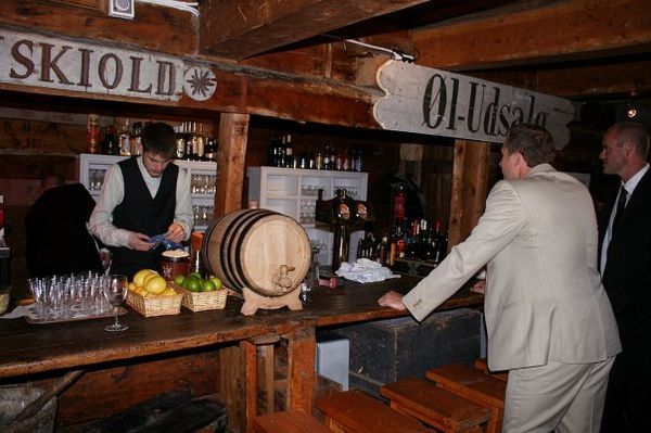 Bartender bak baren med SKIOLD- og Øl-Udsalg-skilt og øltønne