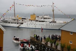 KS Norge ved kai i Hamnvik, med sjaluppen klar ved brygga og folkemengde som venter