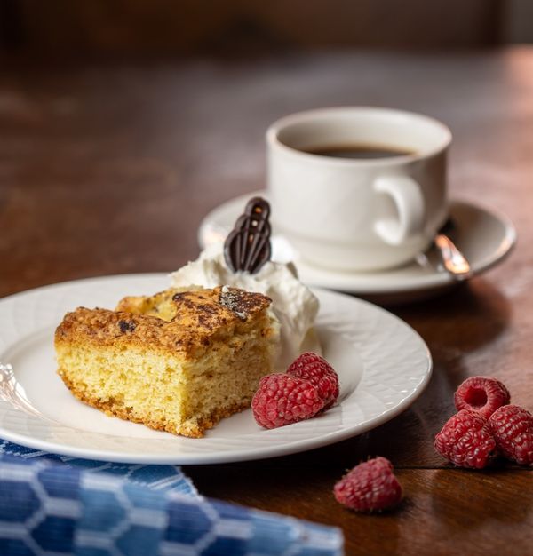 Kakestykke med krem, friske bringebær og kaffekopp