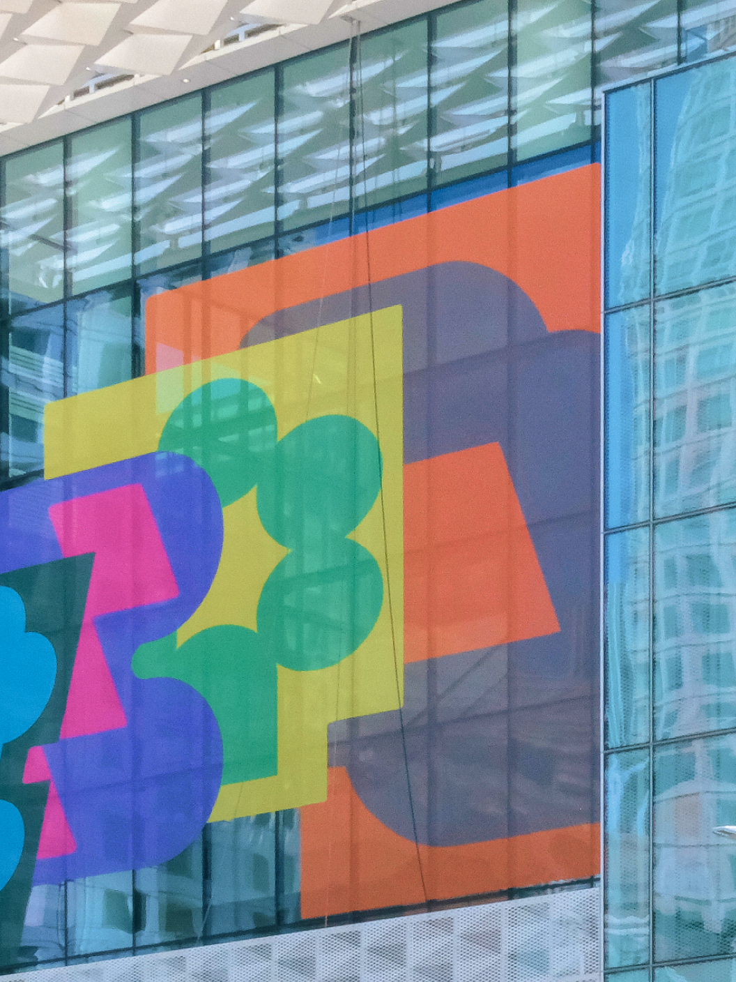 Colorful abstract Config graphics cover Moscone Center glass facade with layered shapes in bright sunlight.
