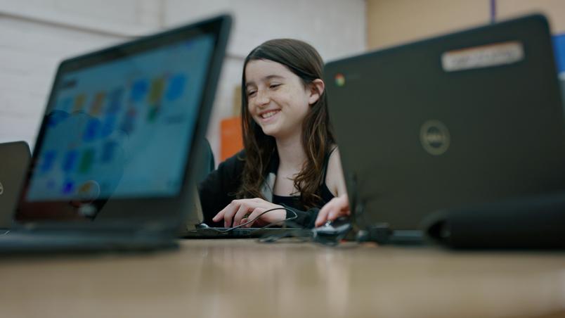 A student smiling in front of a laptop