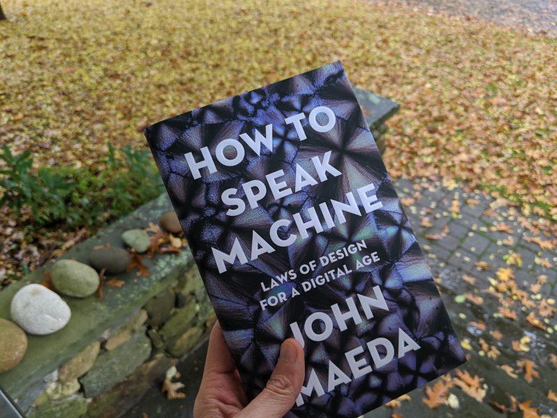 Hand holding book titled "How To Speak Machine"