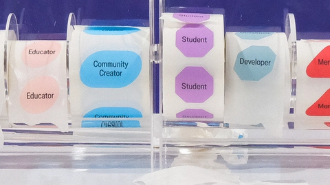 Colorful sticker rolls labeled “Educator,” “Community Creator,” “Student,” “Developer,” and “Mentor” displayed in plastic dispenser