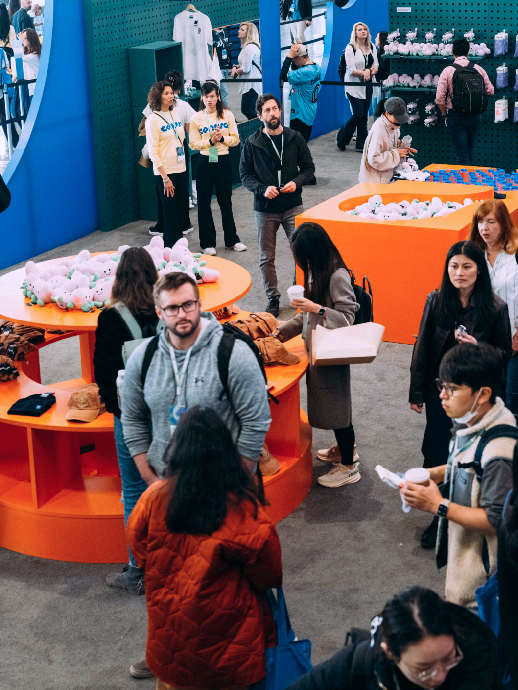 Conference attendees browse colorful Figma merchandise, plushies, and apparel in a lively retail space.