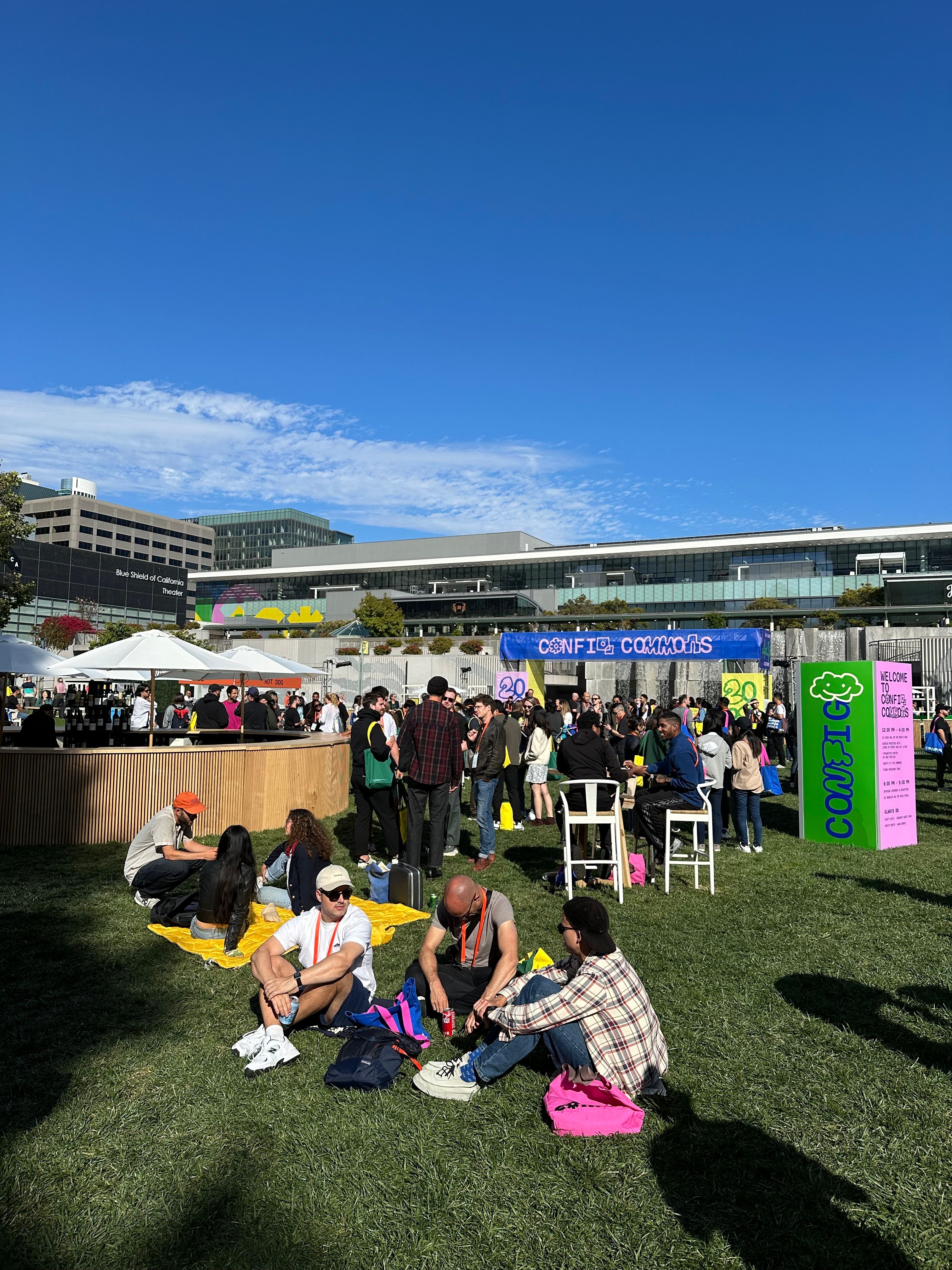 People lounge on the grass and gather at tables at Config Commons.