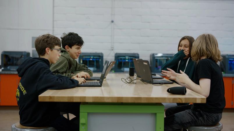 Students sitting around a table with their Chromebooks