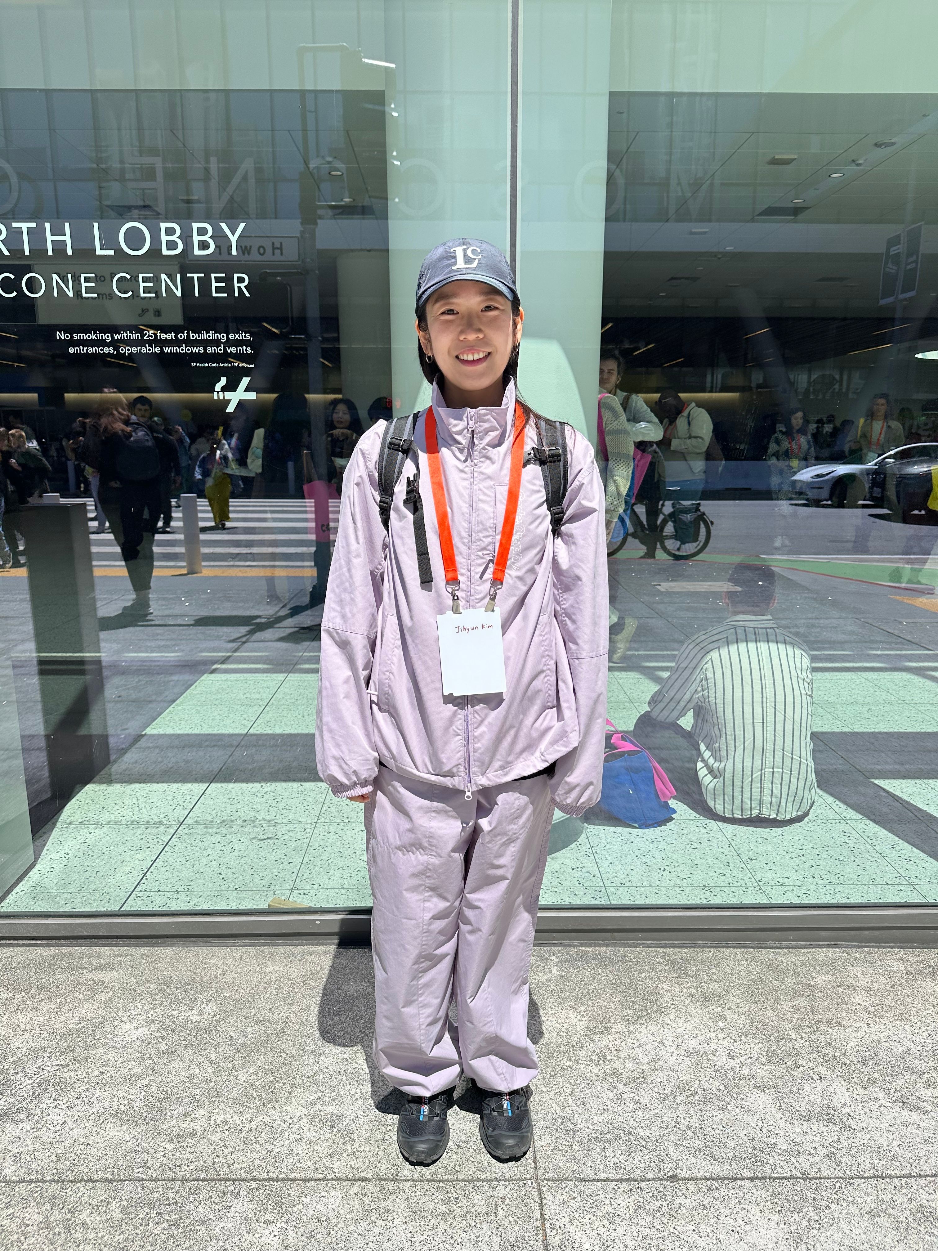 A woman wears a gray cap and lavender tracksuit
