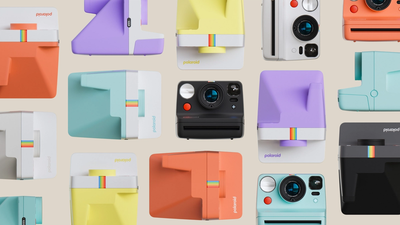 Colorful collection of Polaroid instant cameras and printers in pastel orange, purple, yellow, teal and black