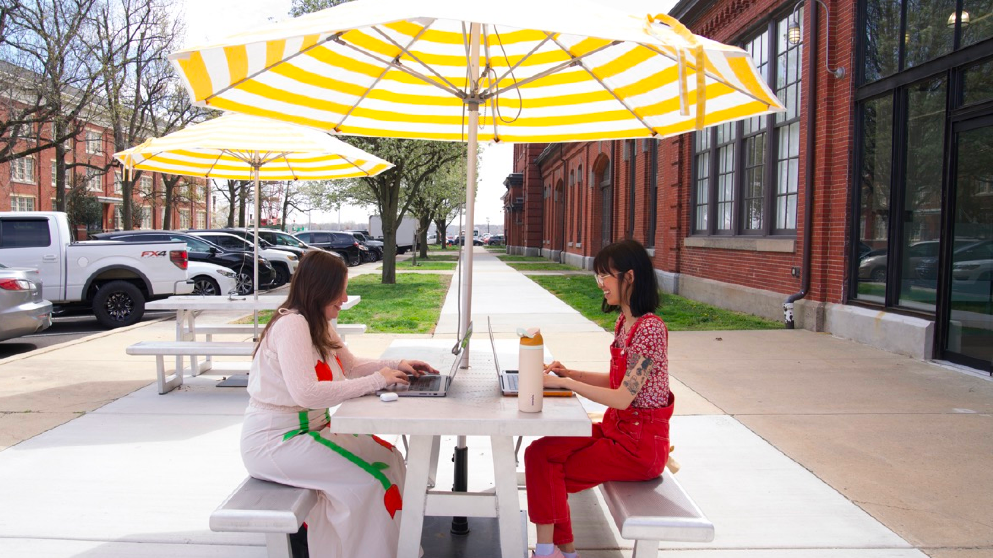 Due dipendenti di Nuuly lavorano sedute a un tavolo all'aperto
