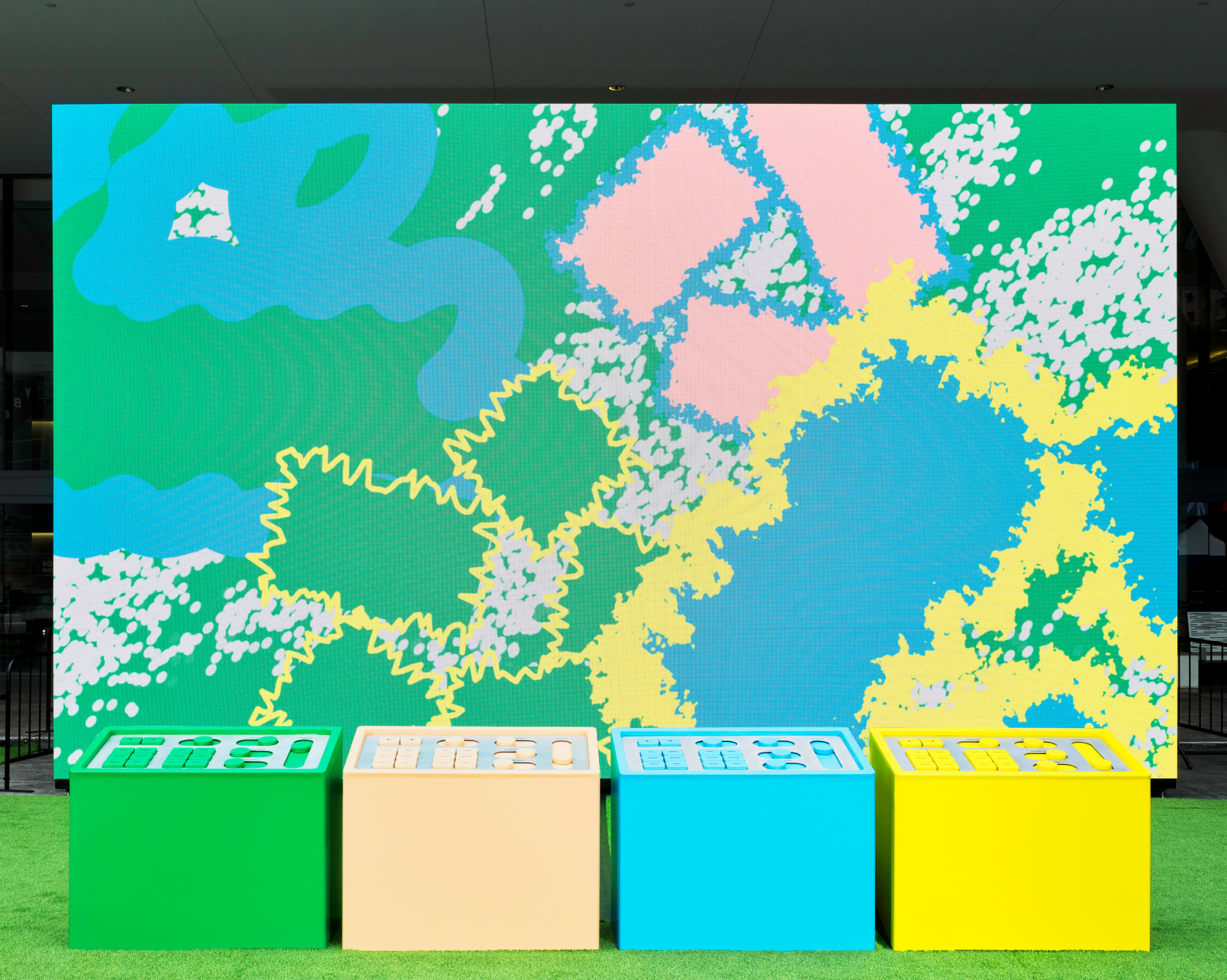 Green, beige, blue, and yellow control panels are arranged in front of a colorful screen