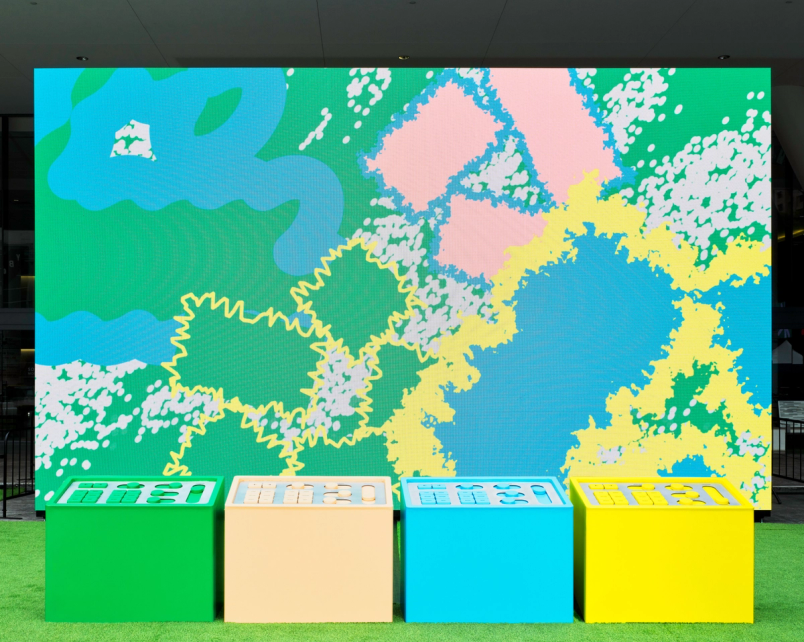 Green, beige, blue, and yellow control panels are arranged in front of a colorful screen