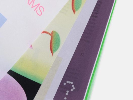 A close-up showing overlapping magazine pages featuring a mix of text and graphics