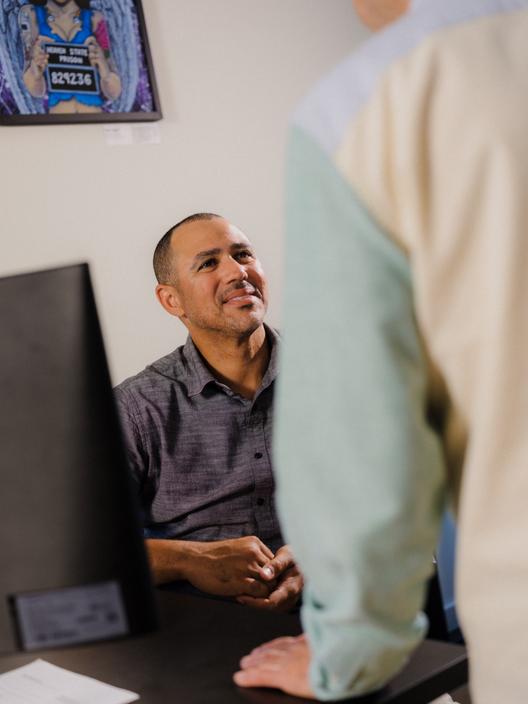 Sitting at a desk, Jason Bryant smiles up at one of the fellows.