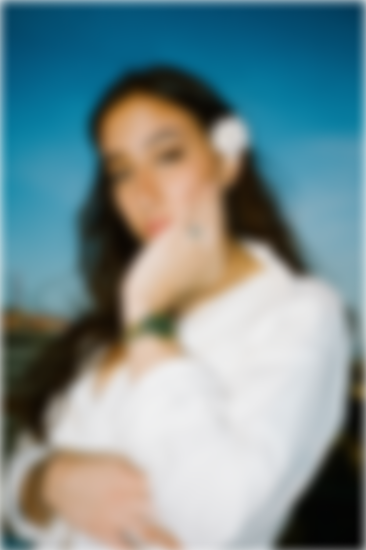 A woman with long hair and a white top is heavily blurred in front of a blue background.