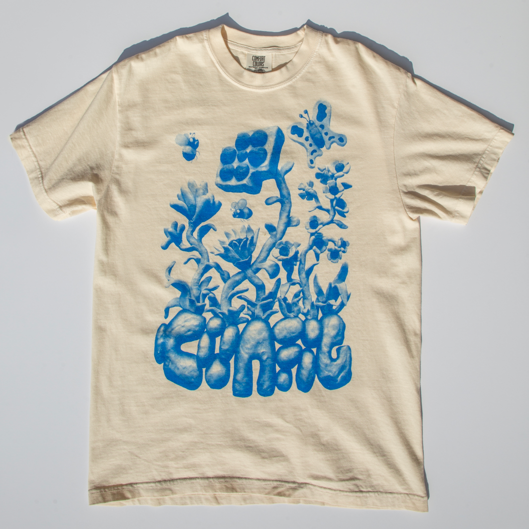 A pale yellow T-shirt with a botanical blue print with bubble letters reading "Config"