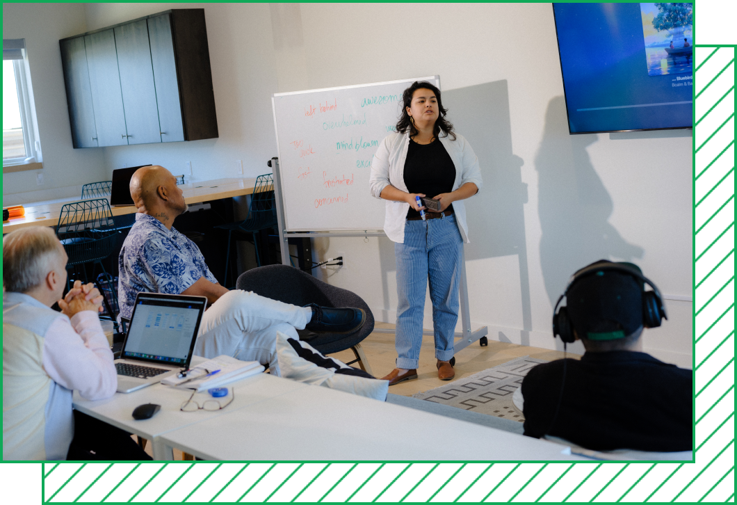 Instructor Alexis Bustos stands in front of a whiteboard in class