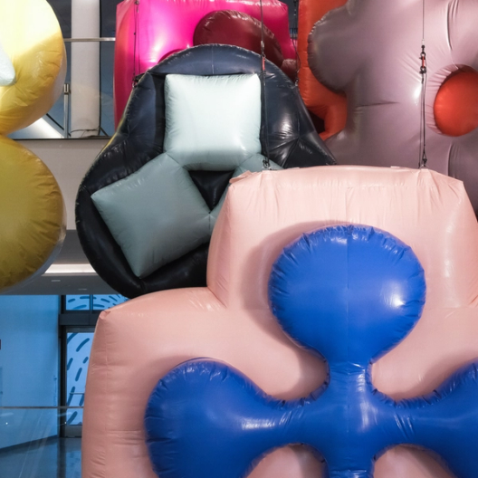 Pink and black inflatable shapes with light blue cushions and a blue center hang in indoor space.
