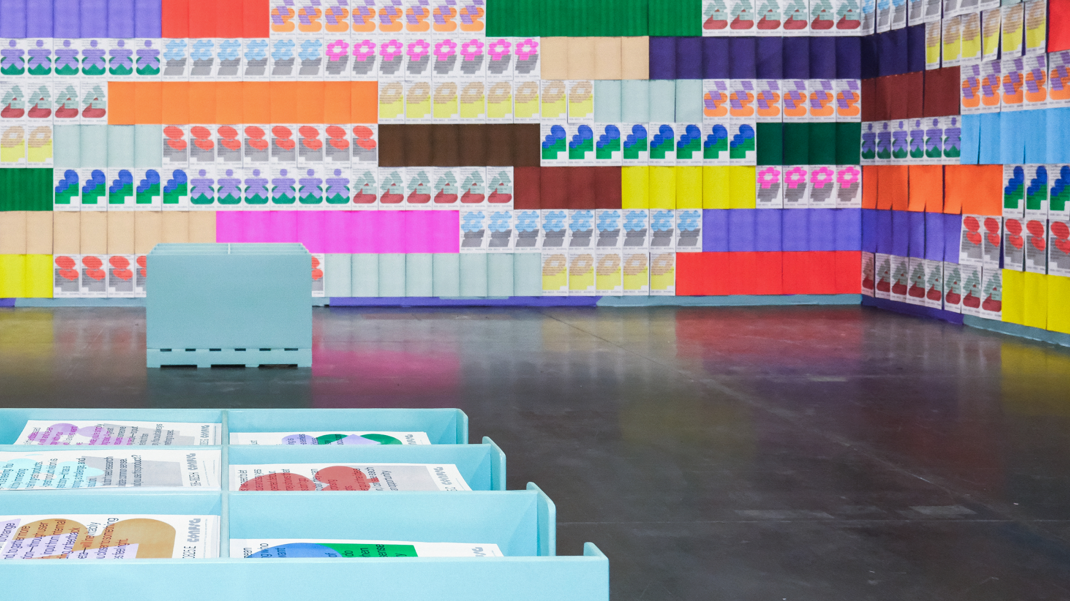 Wide view of multicolored poster wall with Config quote prints and bins for attendees to collect.