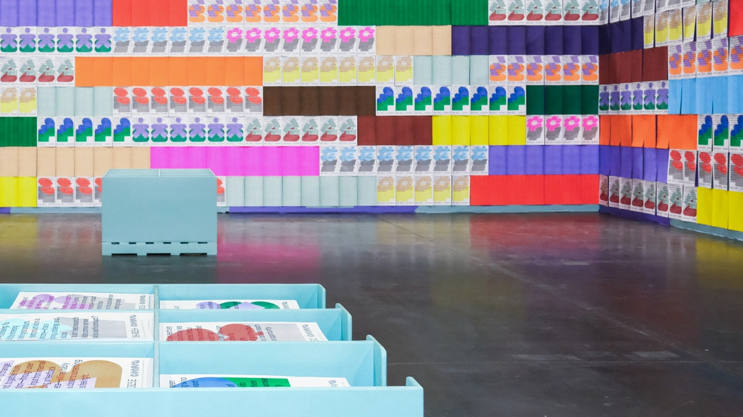 Wide view of multicolored poster wall with Config quote prints and bins for attendees to collect.