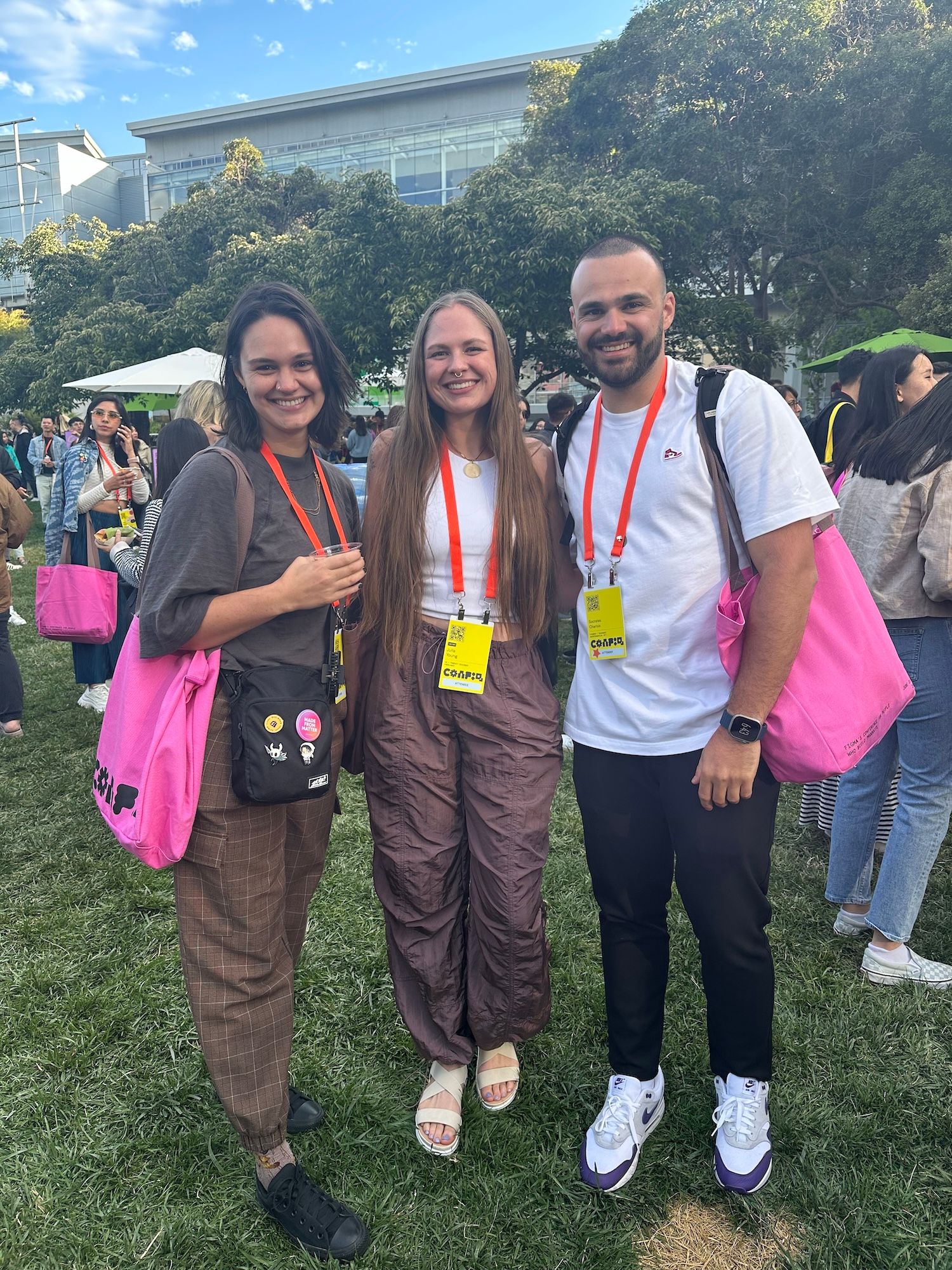 Three people pose at Config Commons with pink tote bags.