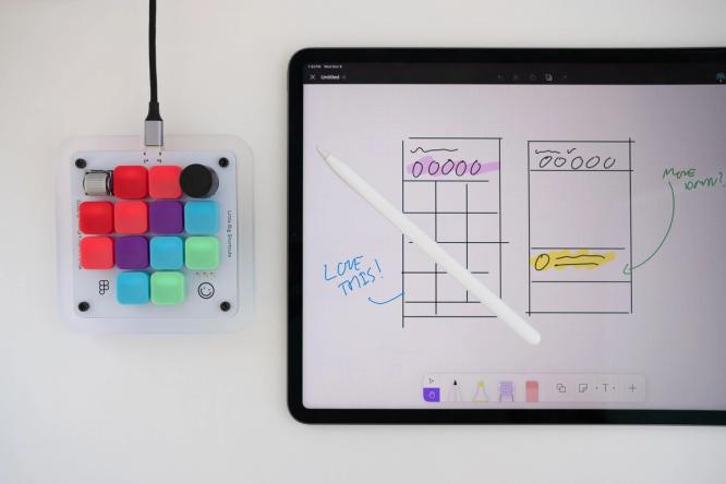 The Figma Creator Micro keyboard on a desk next to an iPad.