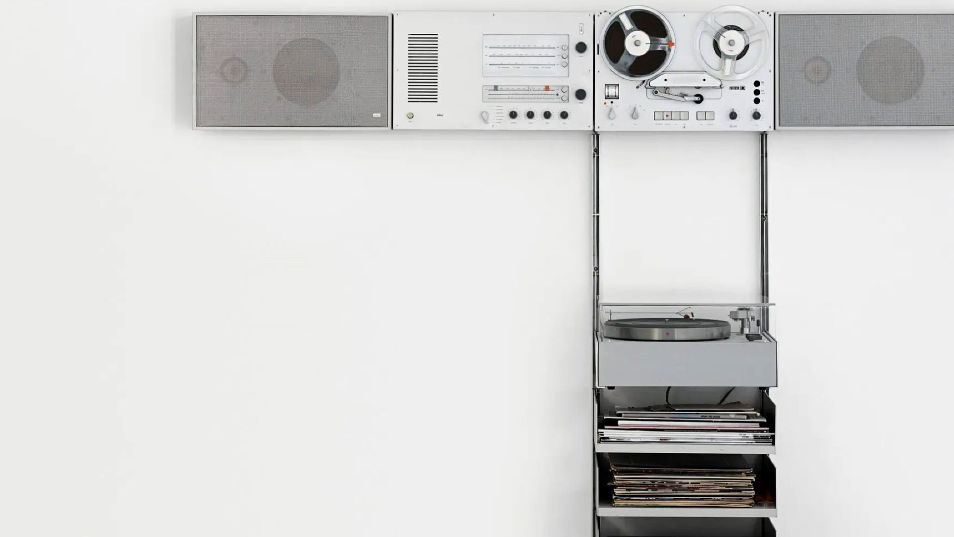 A minimalist Dieter Rams audio system with speakers, reel-to-reel, radio controls, and a turntable neatly integrated into a wall unit.
