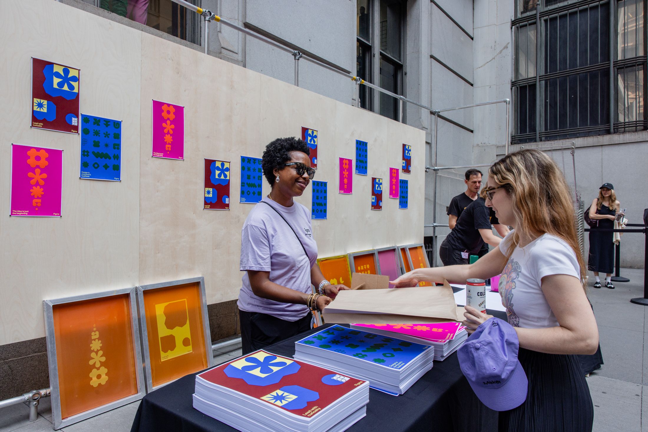 Attendees browse prints at a screen printing station with colorful designs on display.