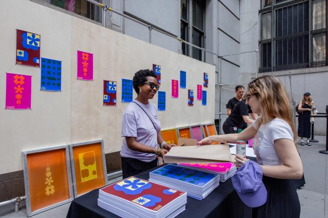 Attendees browse prints at a screen printing station with colorful designs on display.