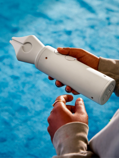 Hands hold a pen-shaped device with buttons