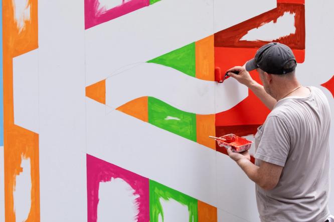 Artist Greg Lamarche painting part of the mural outside the NYSE.
