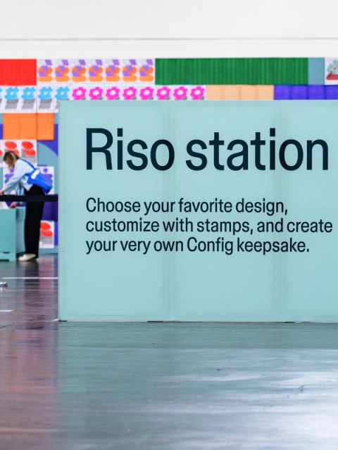 Large sign reads “Riso station” with instructions for creating a personalized Config-themed stamped keepsake.