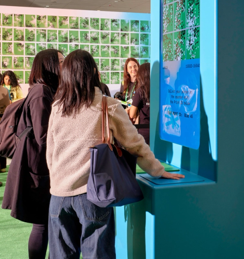 Two people place their hands on a blue kiosk
