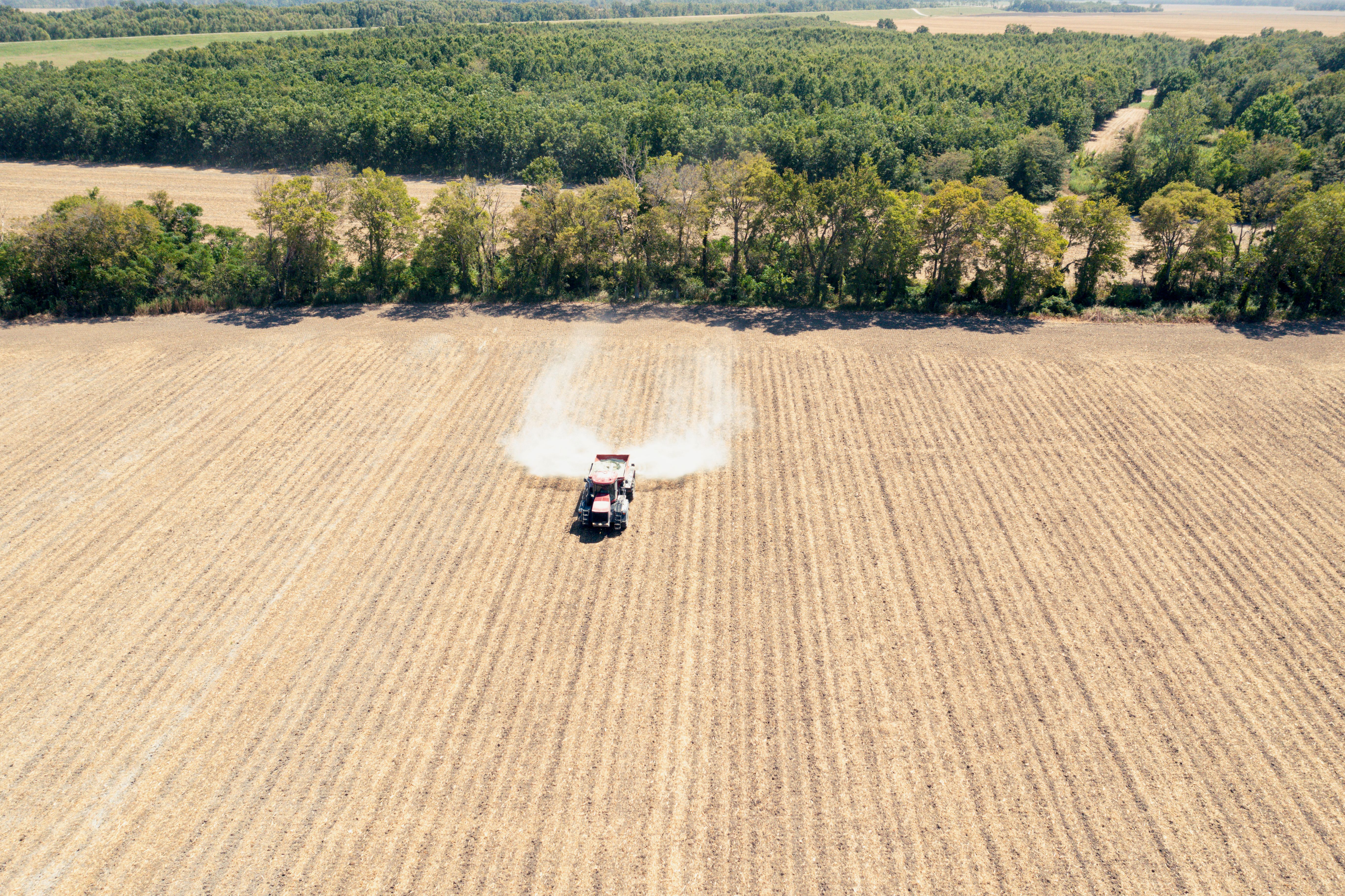 A photograph shows a bird's eye view of a tractor spreading rock powder over crops