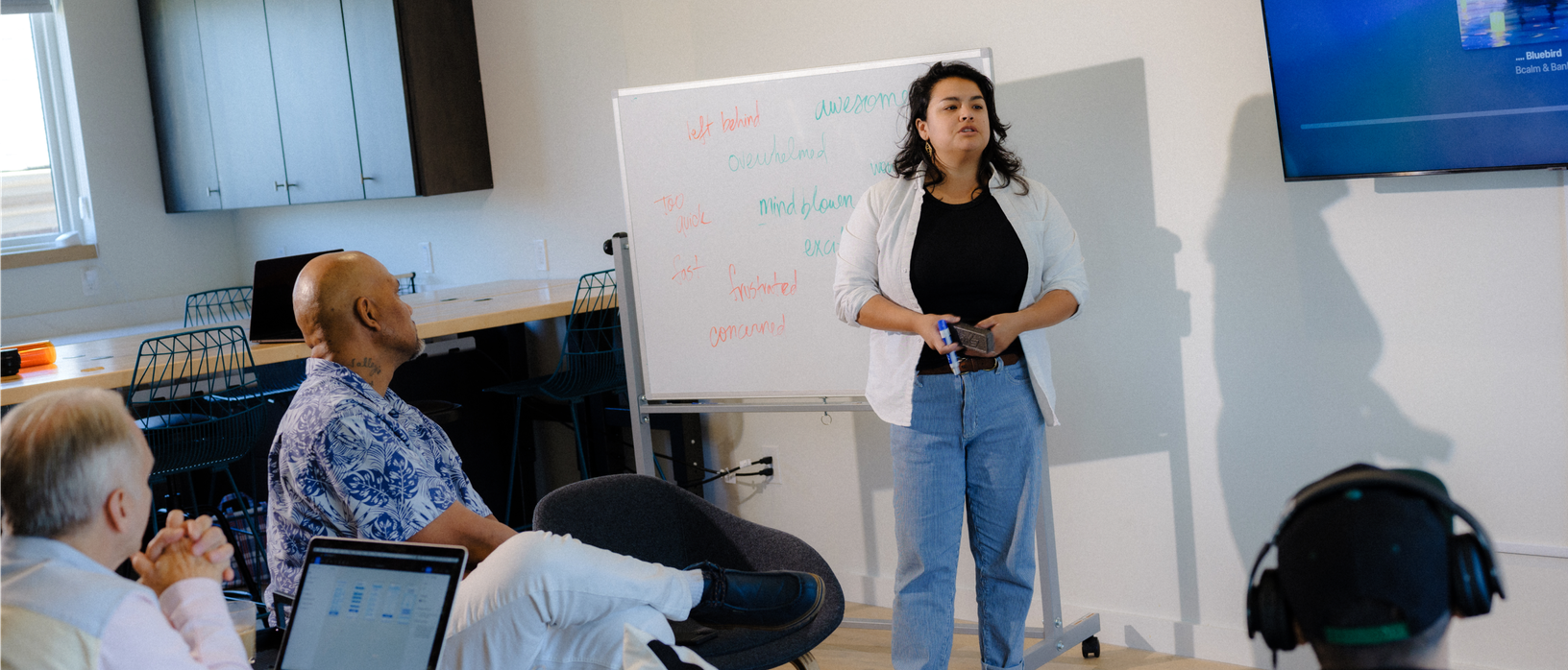 Alexis Bustos stands beside a white board in front of the class.