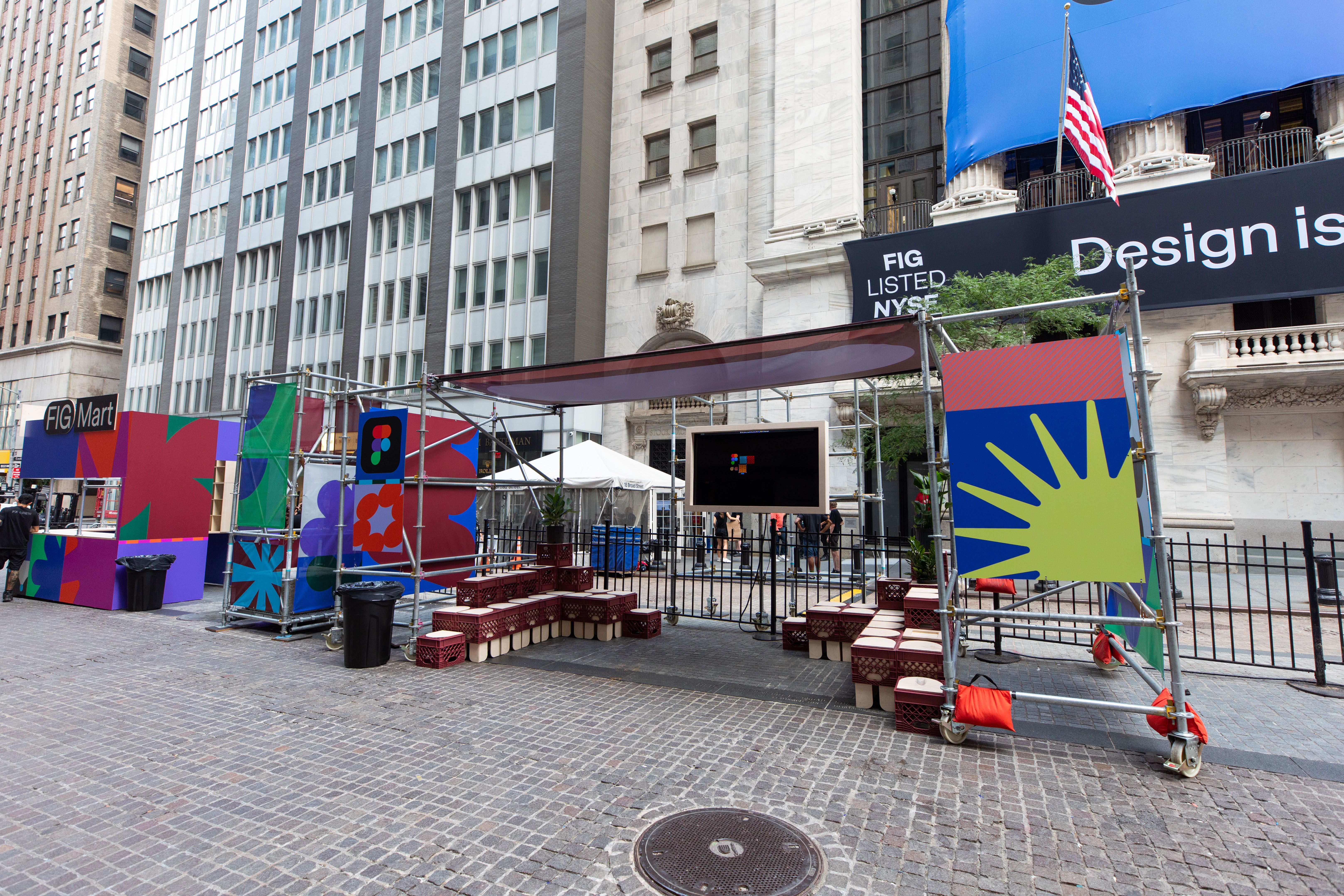 Outdoor installation titled “Figma Commons” in front of the NYSE, with seating, signage, and graphic panels arranged along the street.