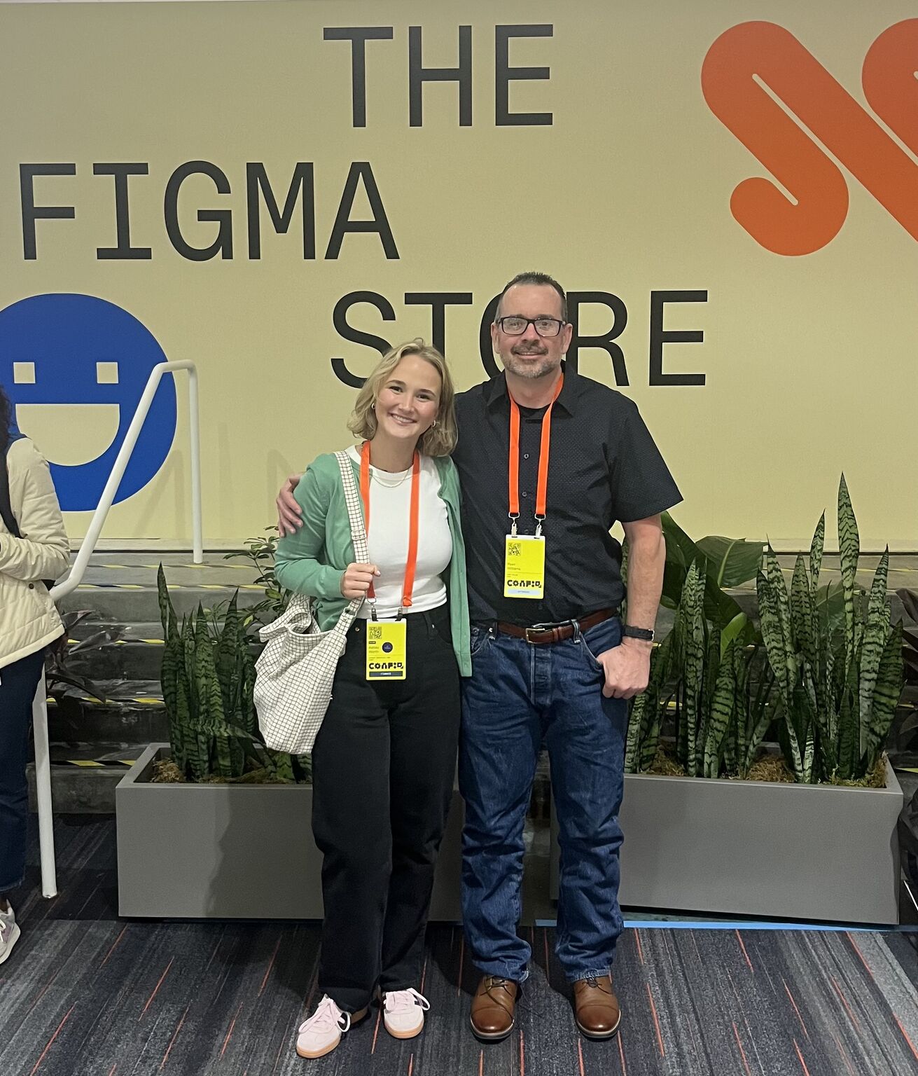 A man and woman pose in front of a sign that says “The Figma Store.”