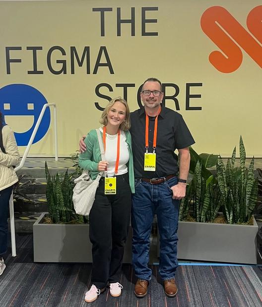A man and woman pose in front of a sign that says “The Figma Store.”