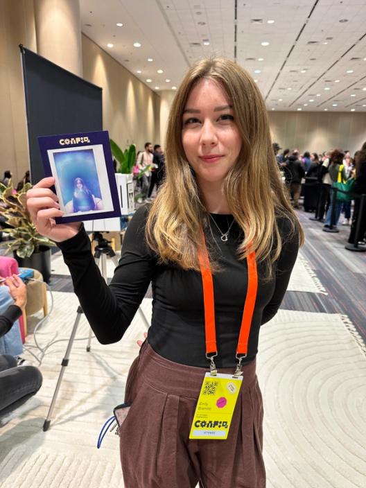 A woman holds up an aura portrait, which shows a blue halo.
