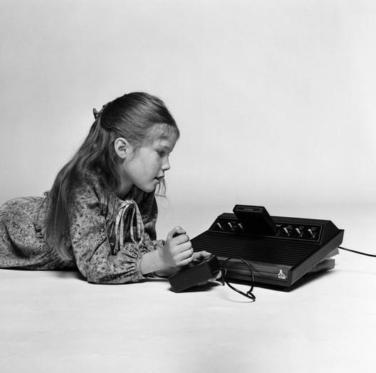 A black-and-white photograph of a girl holding an Atari 2600 joystick.