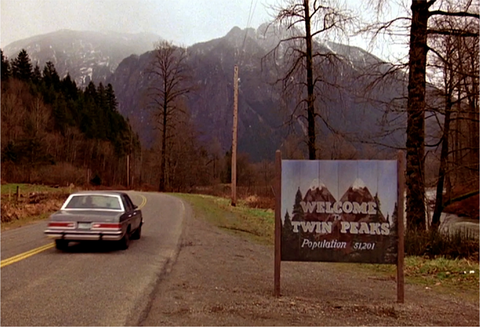ChatGPT said:  A car drives past the “Welcome to Twin Peaks” sign with misty mountains rising in the background.