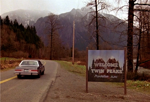 ChatGPT said: A car drives past the “Welcome to Twin Peaks” sign with misty mountains rising in the background.