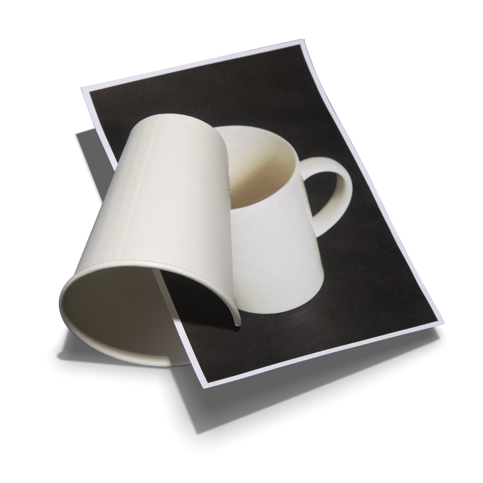 Curved white ceramic mug resting on a printed photo of the same mug, creating a playful visual illusion.