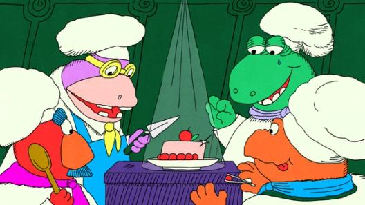 Four cartoon chefs gather around a glowing pink cake with cherries as one prepares to slice it.