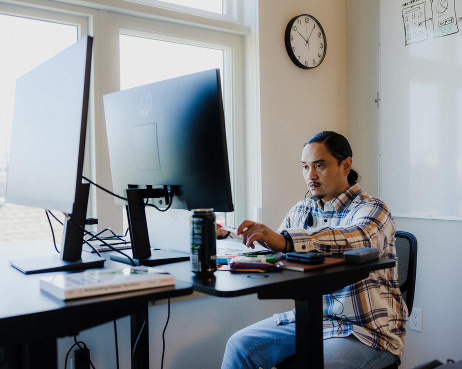 Fellow Pablo Vega sits and works in front of a desktop monitor.