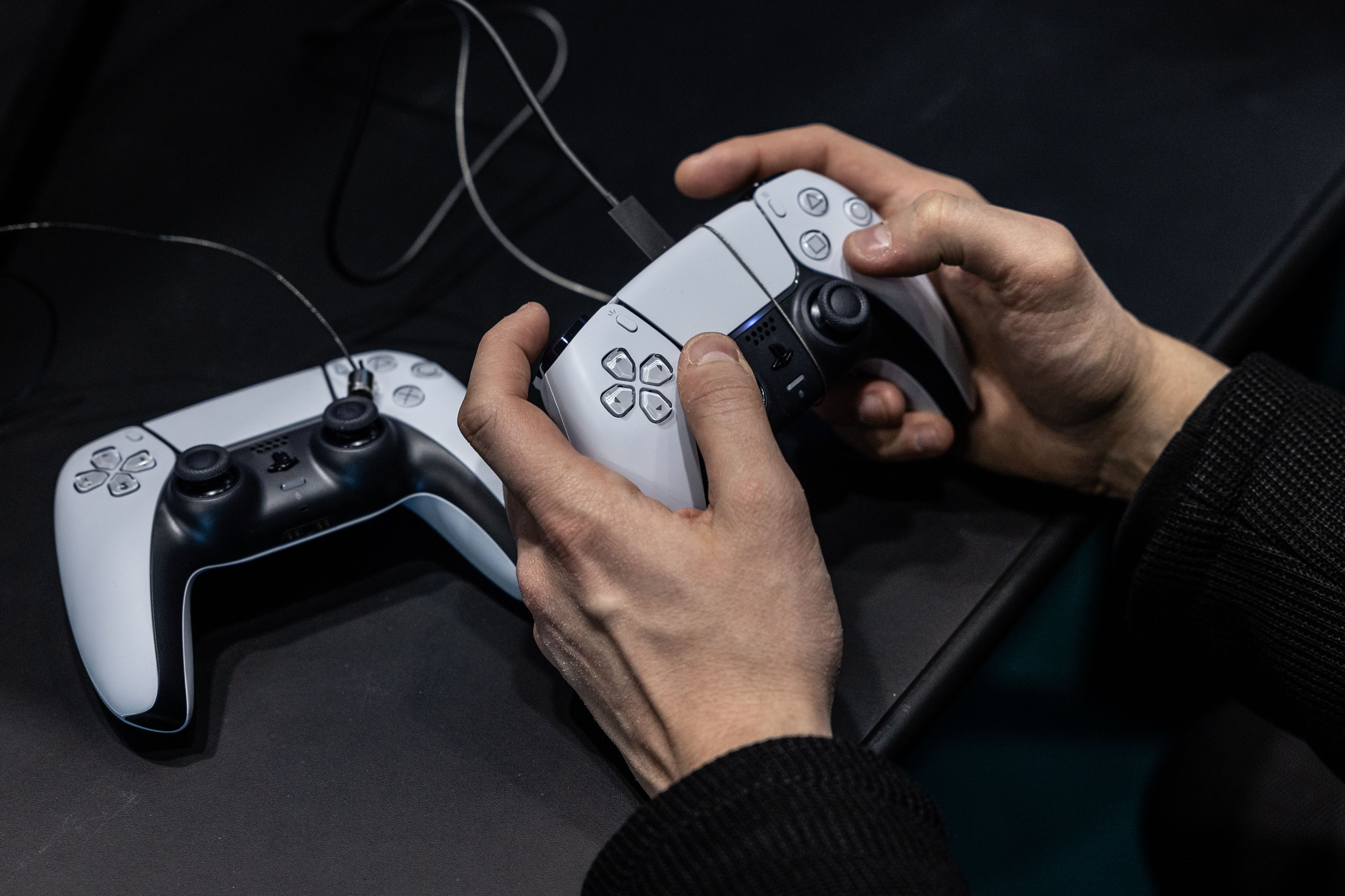 A player’s hands holding a white Playstation 5 controller.