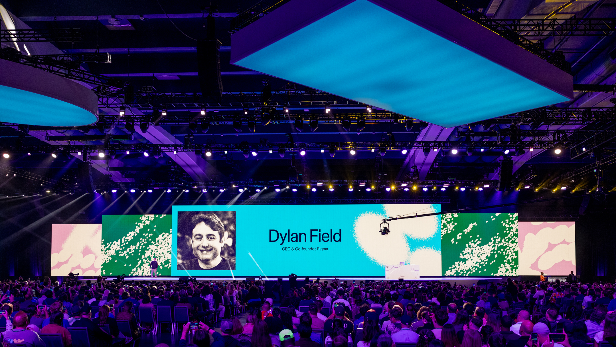 Dylan Field stands on a keynote stage before a large crowd, with a giant screen displaying his photo and title.