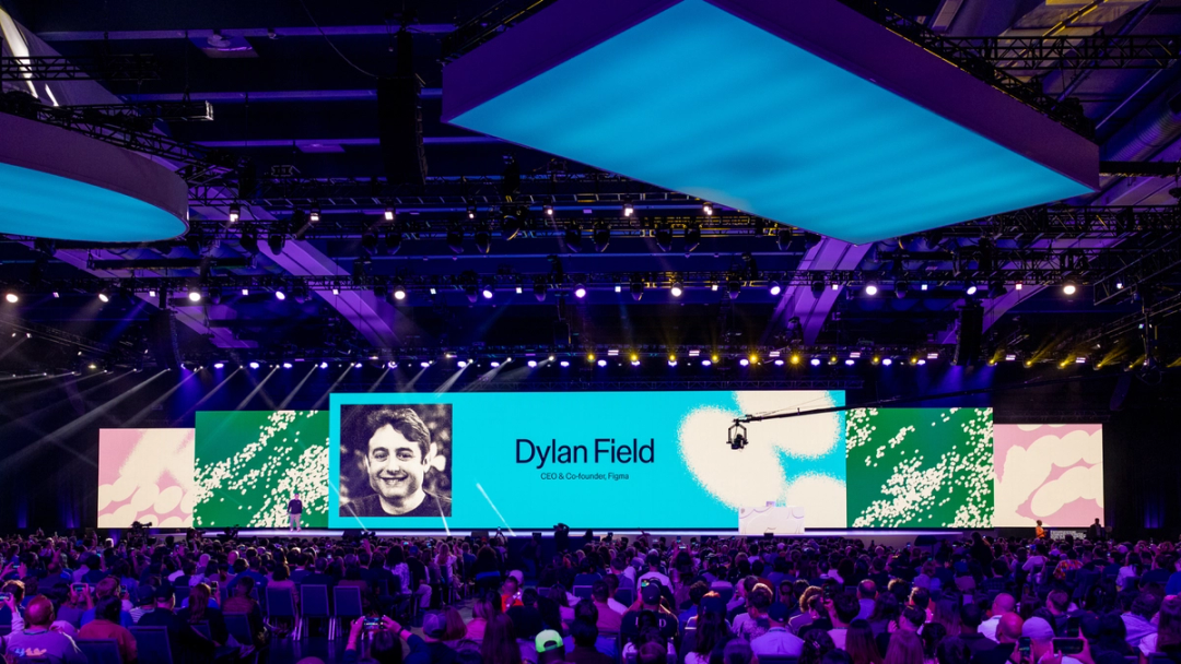 Dylan Field stands on a keynote stage before a large crowd, with a giant screen displaying his photo and title.