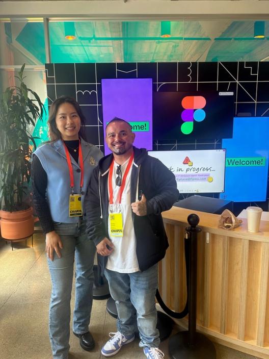 Two people stand smiling at the front desk of an office.