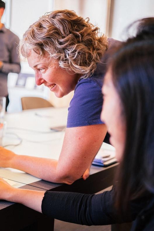 person leaning across a table smiling