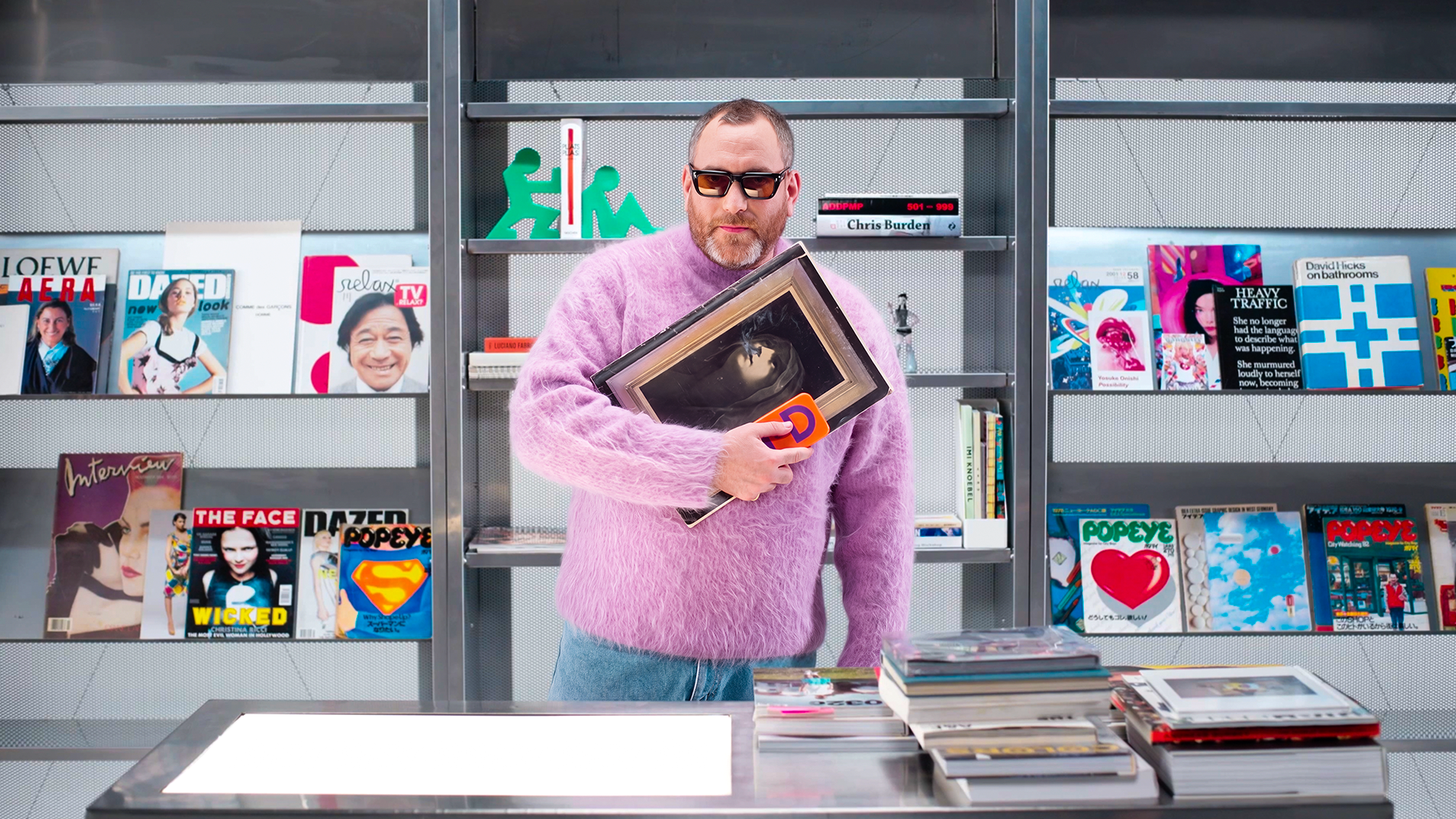Thom Bettridge wears a fuzzy pink sweater holding an artwork